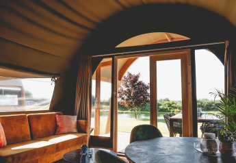 Indvendig udsigt fra en luksus safaritelte på Camping de Bovenberg, med sofa og terrasse i Holland.