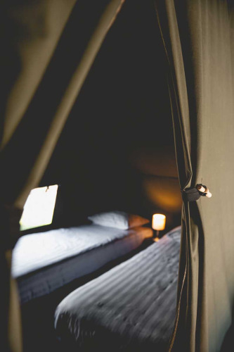 Intérieur d'une tente safari de luxe avec deux lits et lumière douce au Camping de Bovenberg, Pays-Bas.