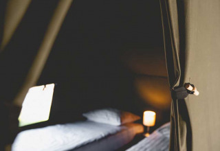 Indersiden af et luksuriøst safaritelte med to senge og blødt lys på Camping de Bovenberg, Holland.