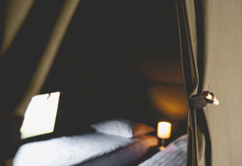 Intérieur d'une tente safari de luxe avec deux lits et lumière douce au Camping de Bovenberg, Pays-Bas.