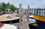 Holzsteg zwischen Booten im Yachthafen von Marina Parcs - Jachthaven De Hoop, Nordholland, Niederlande.