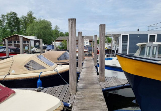 Pasarela de madera entre barcos en Marina Parcs - Jachthaven De Hoop, parque vacacional en Holanda Septentrional.