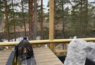 Buitentafel met wijn en glazen in Småland Miniglamping, Kalmar län, Zweden, tussen de bomen.