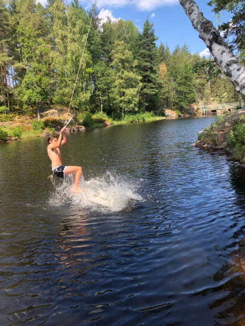 Een jongen zwaait met een touw over een meer in Småland Miniglamping, een vakantiepark in Kalmar län, Zweden.