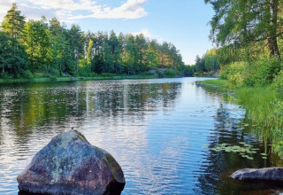 Idyllischer See mit ruhigem Wasser, Felsen und Bäumen bei Gullringen, Kalmar län, Schweden.