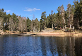Lac paisible entouré d’arbres à Småland Miniglamping dans le Kalmar län, Suède, sous un ciel bleu.