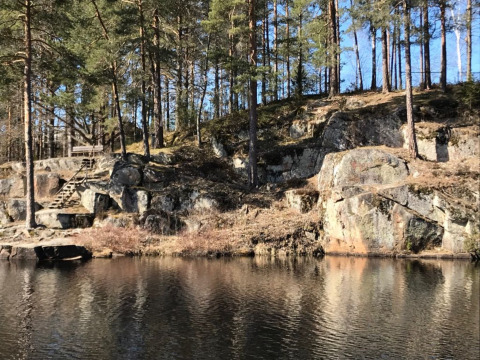 Rotsachtige oever met houten trap en dennenbomen bij Småland Miniglamping, Kalmar län, Zweden.