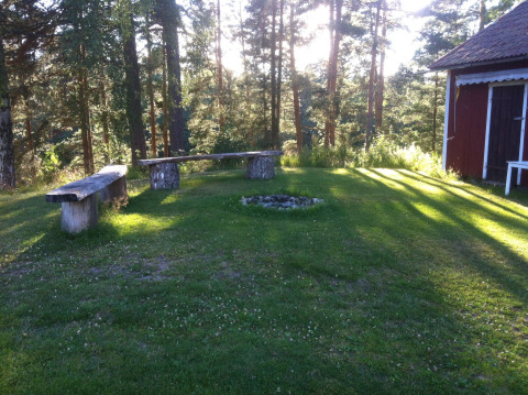 Bancos de madera y área de fogata en Småland Miniglamping, parque vacacional en Kalmar län, Suecia.