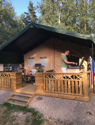 Familia disfruta vida al aire libre en terraza de madera en Småland Miniglamping, Kalmar län, Suecia.
