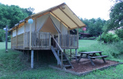 Tienda safari en Camping Sretanwolf, Croacia, con terraza de madera elevada y mesa de picnic al aire libre.