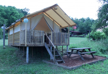 Tenda safari al Camping Sretanwolf in Croazia, veranda in legno rialzata e tavolo da picnic nel verde.