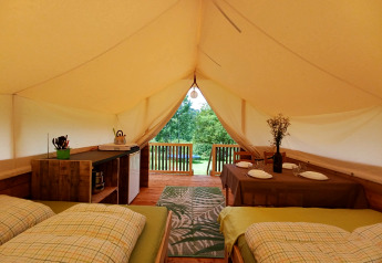 Interior of the Safari tent at Camping Sretanwolf in Croatia with beds, dining table, and a wooden deck.