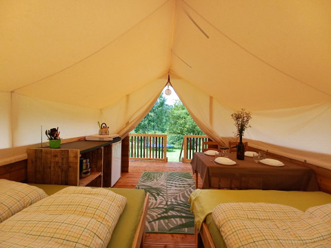 Interior de la tienda Safari en Camping Sretanwolf, Croacia, con camas, mesa de comedor y terraza.