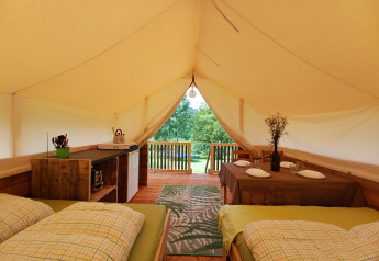 Interior de la tienda Safari en Camping Sretanwolf, Croacia, con camas, mesa de comedor y terraza.