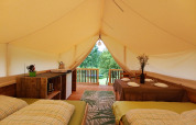 Interior de la tienda Safari en Camping Sretanwolf, Croacia, con camas, mesa de comedor y terraza.