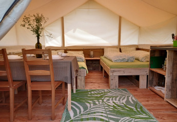 Indretning af en safaritelt-lodge med to senge, spisebord og et køkkenområde på Camping Sretanwolf i Kroatien.