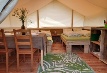 Interior de tienda safari con camas, mesa de comedor y zona de cocina en Camping Sretanwolf en Croacia.