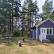 Blå træhytte omgivet af skov, græsplæne og høns ved Stuga glamping, Småland Miniglamping, Sverige.