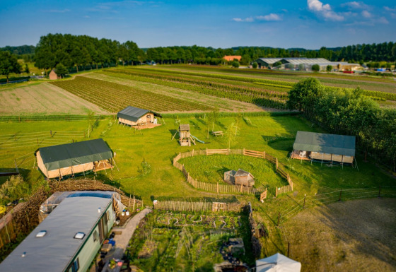 Vista aerea del parco vacanze Hoeve Klein Haneveld nel Brabante Settentrionale, Paesi Bassi, con campi verdi.