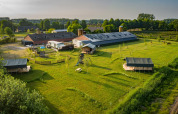 Luftfoto af Hoeve Klein Haneveld feriepark i Nord-Brabant, Nederlandene, med marker, bygninger og telte.