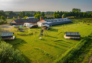 Vista aerea del parco vacanze Hoeve Klein Haneveld nel Brabante Settentrionale, Paesi Bassi, con campi e tende.