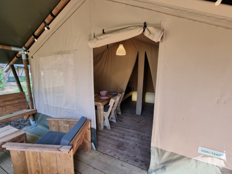 Tienda safari con muebles de madera, acceso al área de estar y comedor, espacio de dormitorio al fondo.