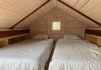 Accogliente stanza mansardata con due letti singoli in Stuga glamping presso Småland Miniglamping, Svezia.