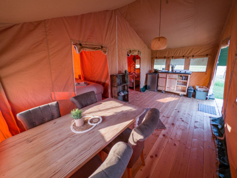 Vista interior de una tienda safari en Hoeve Klein Haneveld, Países Bajos, con comedor y zona de cocina.