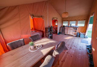 Vista interior de una tienda safari en Hoeve Klein Haneveld, Países Bajos, con comedor y zona de cocina.