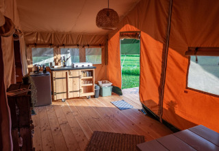 Vista interior de una acogedora tienda safari con suelo de madera y cocina en Hoeve Klein Haneveld, Países Bajos.