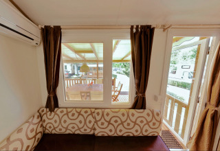 Vista interior de SunLodge Maple glamping con sofá decorado, cortinas y acceso a una terraza techada.