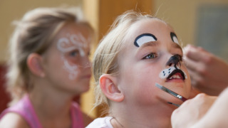 Children get their faces painted as a cat and a butterfly at Camping Bella Austria in Styria, Austria.