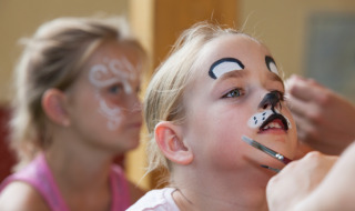 Children get their faces painted as a cat and a butterfly at Camping Bella Austria in Styria, Austria.