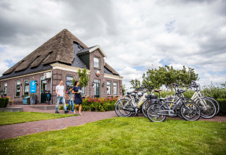 Wandelaars bij fietsen en een rietgedekt huis in Park Westerkogge, Noord-Holland, Nederland.