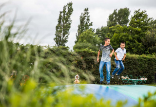 Two boys joyfully bounce on a large inflatable pillow at Park Westerkogge, North-Holland, Netherlands.