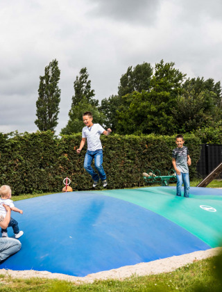 Børn og voksne leger på en stor oppustelig pude på legepladsen i Park Westerkogge, Nordholland, Holland.