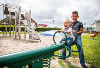 Due bambini giocano sull’altalena nel parco giochi a Park Westerkogge, Olanda Settentrionale, Paesi Bassi.