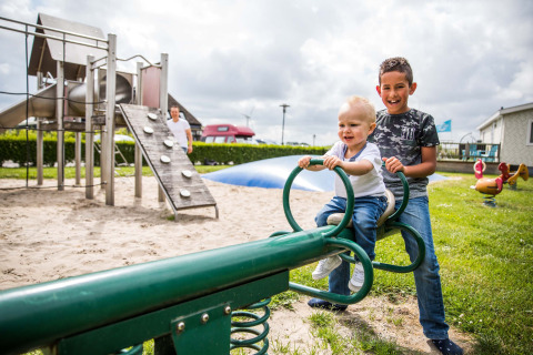 Zwei Kinder spielen auf einer Wippe auf dem Spielplatz im Park Westerkogge in Nordholland, Niederlande.
