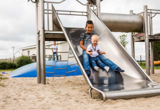 Twee kinderen glijden samen van een glijbaan in Park Westerkogge, vakantiepark in Noord-Holland, Nederland.