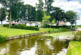 Casas de vacaciones junto al agua y césped verde en Park Westerkogge, un parque vacacional en Holanda del Norte.
