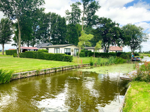 Holiday cottages by the water and green lawns at Park Westerkogge, a holiday park in North Holland, Netherlands.
