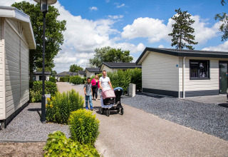 Gezin wandelt rond de chalets van vakantiepark Westerkogge in Noord-Holland, Nederland, bij mooi weer.