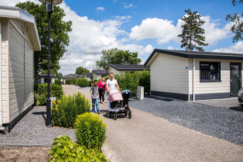 Familie spaziert durch den Ferienpark Westerkogge in Nordholland, Niederlande, an einem sonnigen Tag.