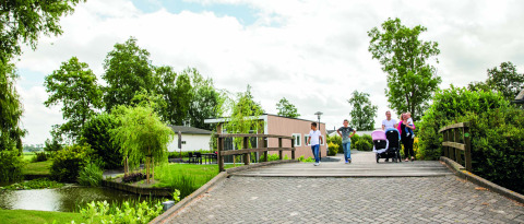 Familia cruzando un puente en Park Westerkogge, un parque vacacional en un entorno verde en el norte de Holanda.