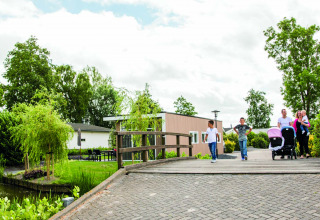 Gezin steekt brug over in Park Westerkogge, een vakantiepark omgeven door groen in Noord-Holland, Nederland.