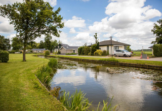 Vakantiepark Westerkogge in Noord-Holland, Nederland, met kanaal, gras en charmante huisjes.