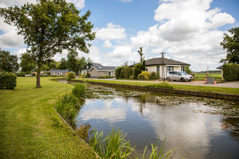 Vakantiepark Westerkogge in Noord-Holland, Nederland, met kanaal, gras en charmante huisjes.