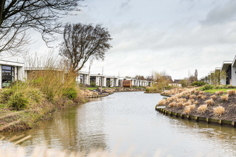 Case vacanza lungo un canale con rive erbose al Park Westerkogge, Olanda Settentrionale, Paesi Bassi.
