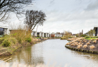 Case vacanza lungo un canale con rive erbose al Park Westerkogge, Olanda Settentrionale, Paesi Bassi.