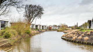 Casas de vacaciones junto a un canal bordeado de hierba en Park Westerkogge, Holanda Septentrional.